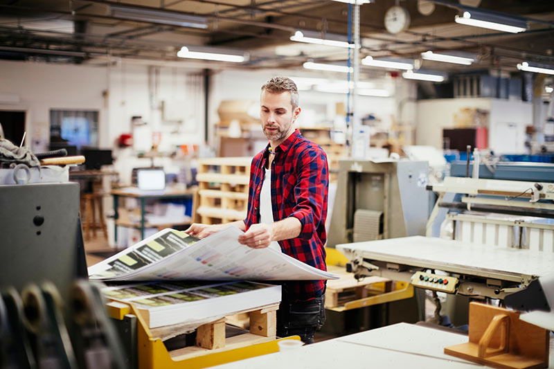 worker checking large format prints at a print lab