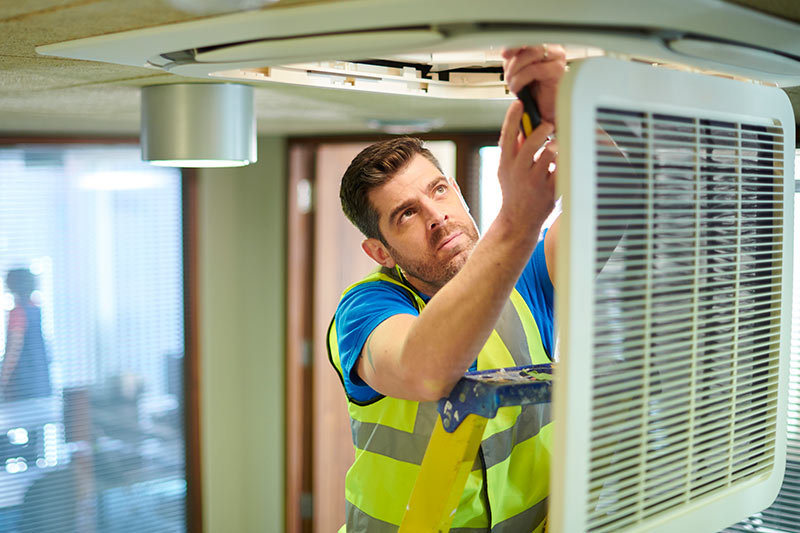 hvac business owner installing equipment in ceiling