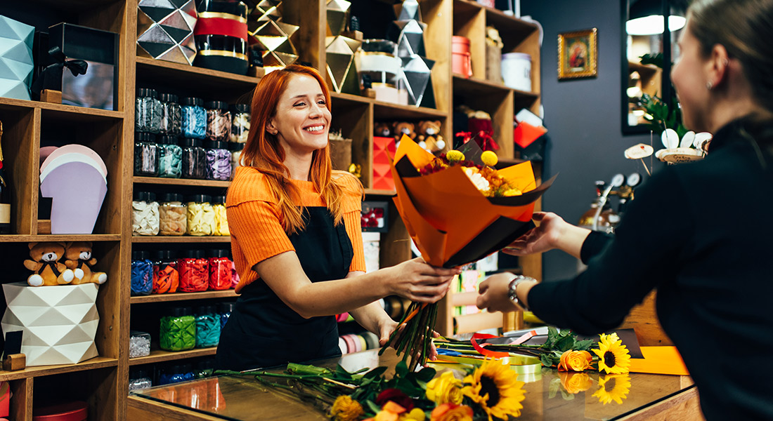 floral business owner handing a flower bouquet to a customer, end-of-summer business funding tips