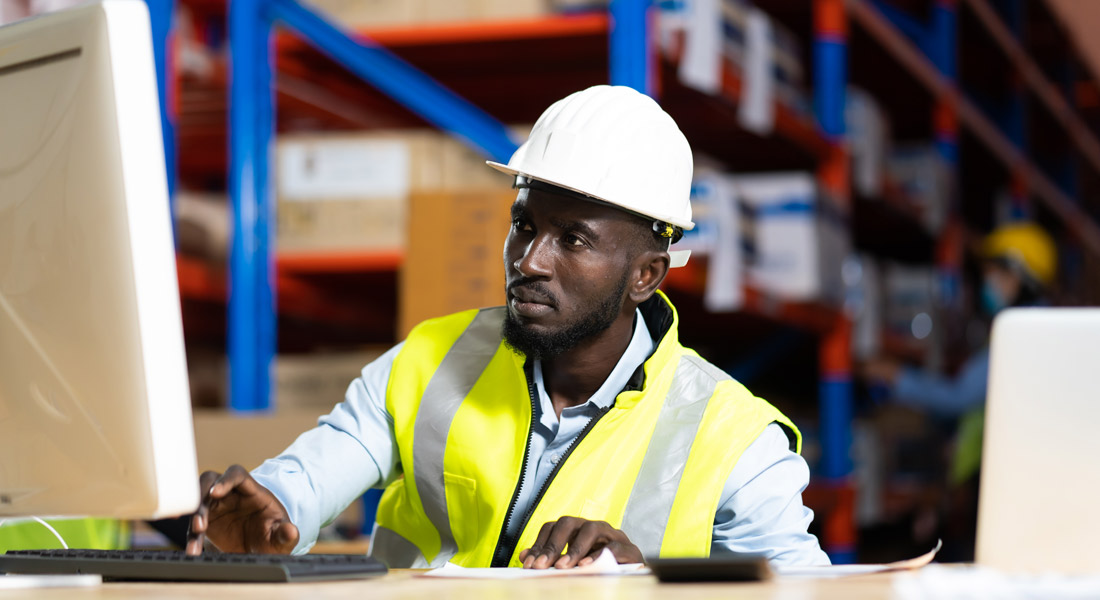 Vendor manager using computer in a large warehouse. Five cybersecurity strategies for equipment vendors.