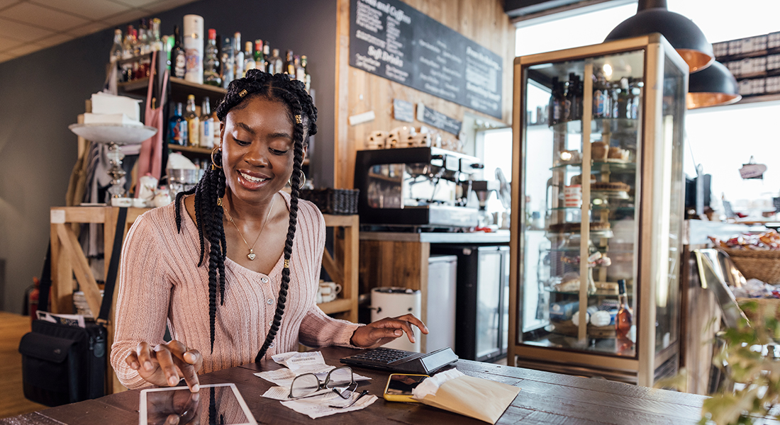 A smiling small-business owner calculating finances inside the retail store.